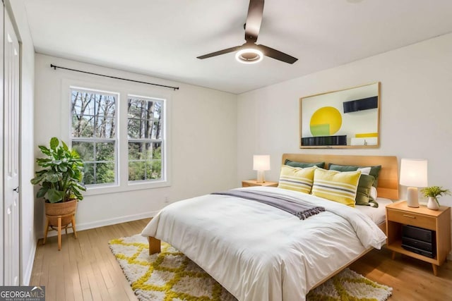 bedroom with ceiling fan, wood finished floors, and baseboards