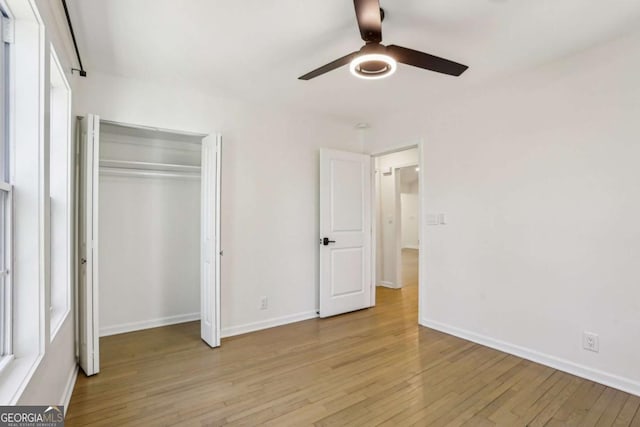 unfurnished bedroom with light wood-style floors, a closet, baseboards, and a ceiling fan