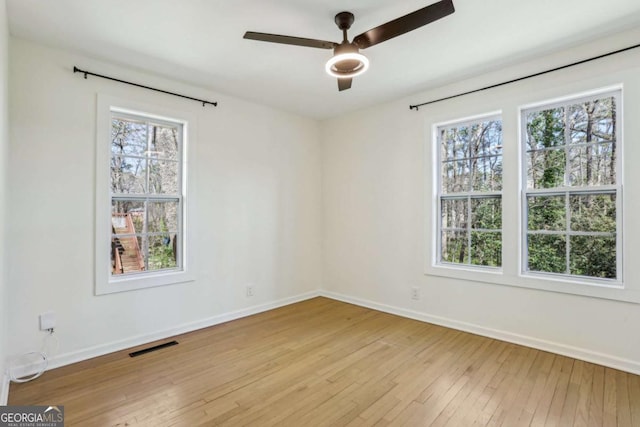 unfurnished room with a ceiling fan, light wood-style flooring, visible vents, and baseboards