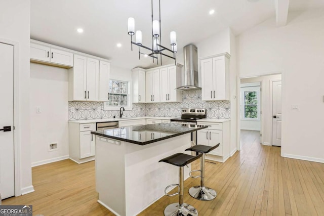 kitchen with tasteful backsplash, stainless steel electric range oven, light wood-style flooring, and wall chimney exhaust hood