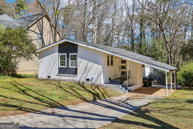 mid-century inspired home featuring driveway, an attached carport, a front lawn, board and batten siding, and brick siding