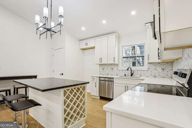 kitchen with light wood finished floors, decorative backsplash, stainless steel dishwasher, white cabinetry, and a sink