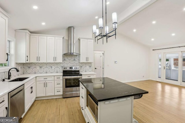 kitchen with vaulted ceiling with beams, stainless steel appliances, a sink, wall chimney range hood, and decorative backsplash