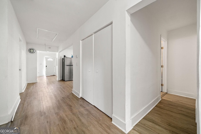 hallway with attic access, baseboards, and wood finished floors