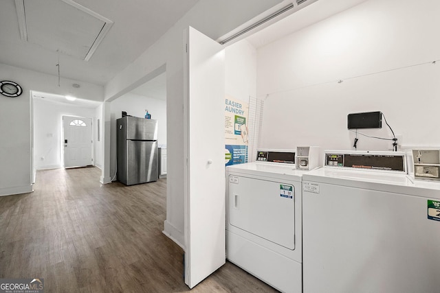 common laundry area with attic access, baseboards, wood finished floors, and independent washer and dryer