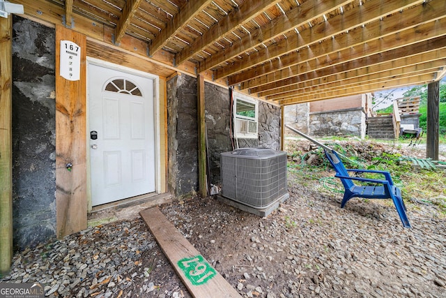 entrance to property featuring central air condition unit, stone siding, and cooling unit