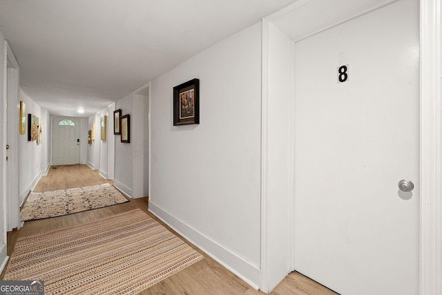 corridor with baseboards and light wood finished floors