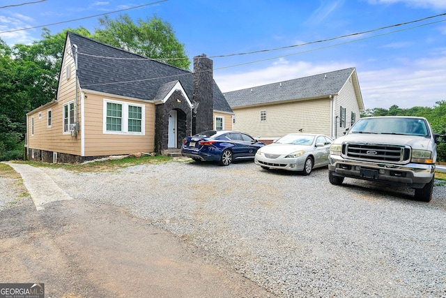 view of front of house with a shingled roof and a chimney