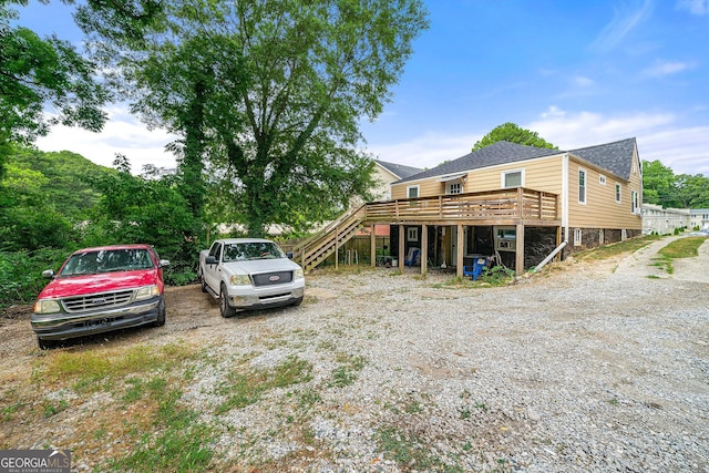 view of front of house featuring a shingled roof, a deck, and stairs