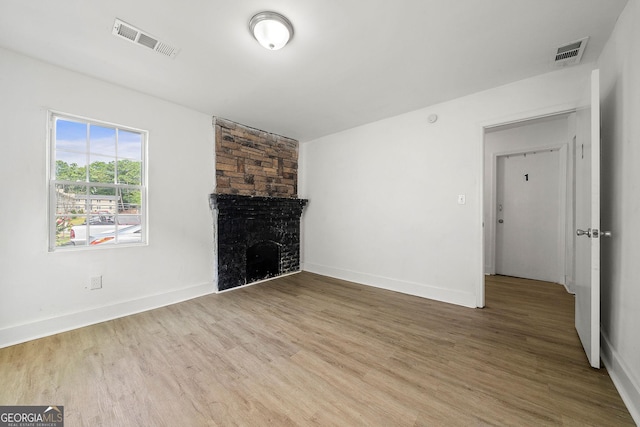 unfurnished living room with baseboards, a fireplace, visible vents, and wood finished floors