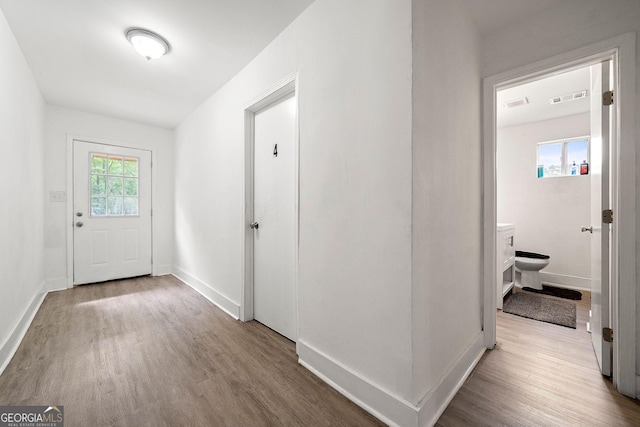 hall featuring visible vents, baseboards, and wood finished floors