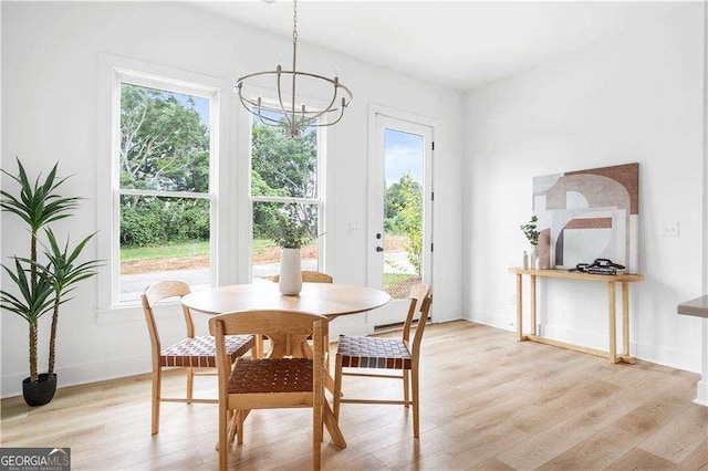 dining space featuring light wood-style floors, baseboards, and a chandelier