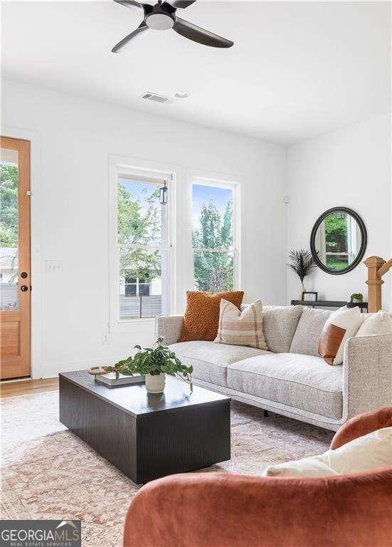 living area with light wood-style floors, visible vents, and a ceiling fan