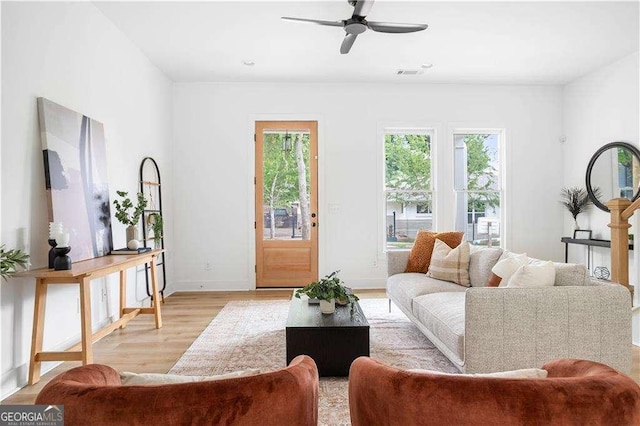 living area with ceiling fan, light wood-type flooring, visible vents, and baseboards