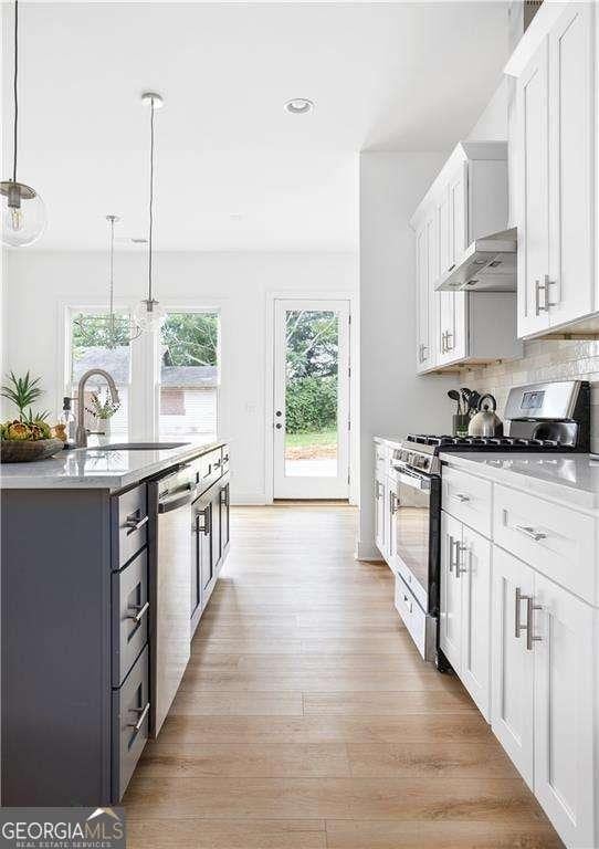 kitchen featuring extractor fan, stainless steel appliances, a sink, white cabinets, and light wood finished floors