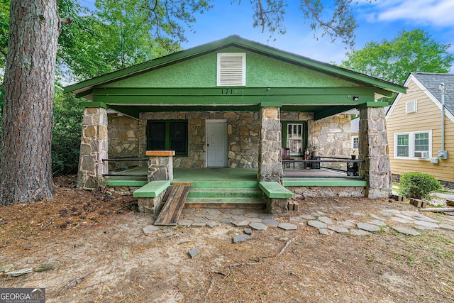 rear view of property with a porch, stone siding, and stucco siding