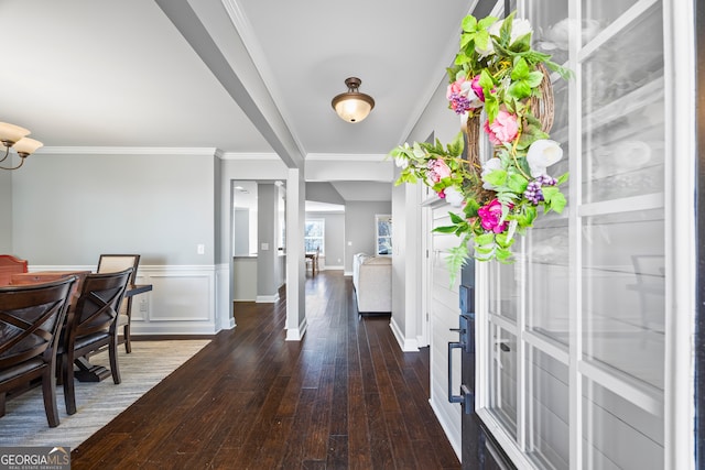 entrance foyer featuring baseboards, wainscoting, hardwood / wood-style flooring, crown molding, and a decorative wall