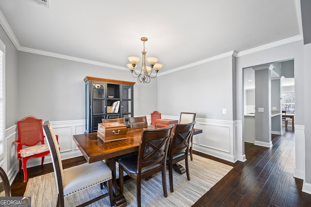 dining area featuring a wainscoted wall, a chandelier, wood finished floors, and ornamental molding