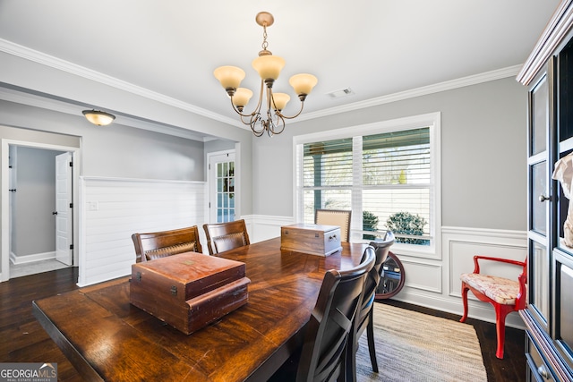 dining area featuring visible vents, a wainscoted wall, wood finished floors, an inviting chandelier, and crown molding