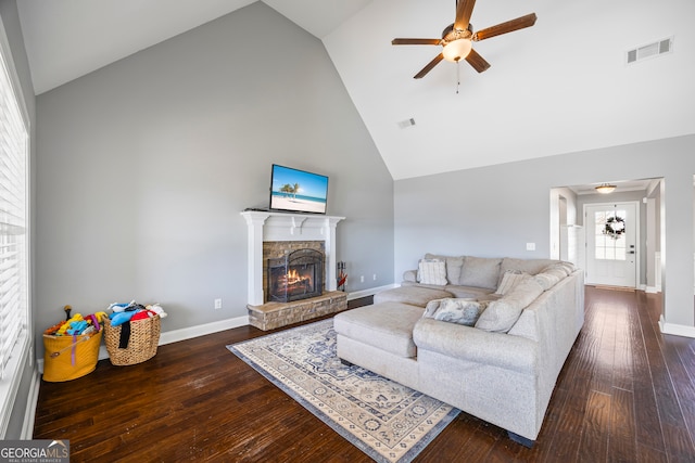 living room featuring dark wood-style flooring, a fireplace, visible vents, a ceiling fan, and high vaulted ceiling