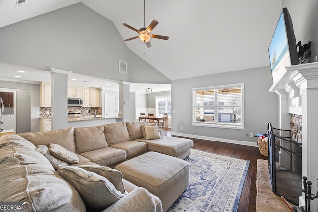 living room featuring visible vents, dark wood finished floors, ornate columns, a fireplace, and high vaulted ceiling