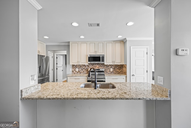 kitchen featuring visible vents, appliances with stainless steel finishes, ornamental molding, cream cabinetry, and a sink