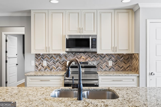 kitchen featuring appliances with stainless steel finishes, crown molding, a sink, and light stone countertops