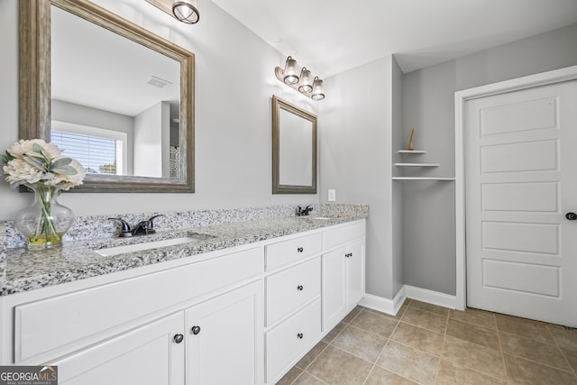 bathroom with a sink, visible vents, baseboards, tile patterned floors, and double vanity