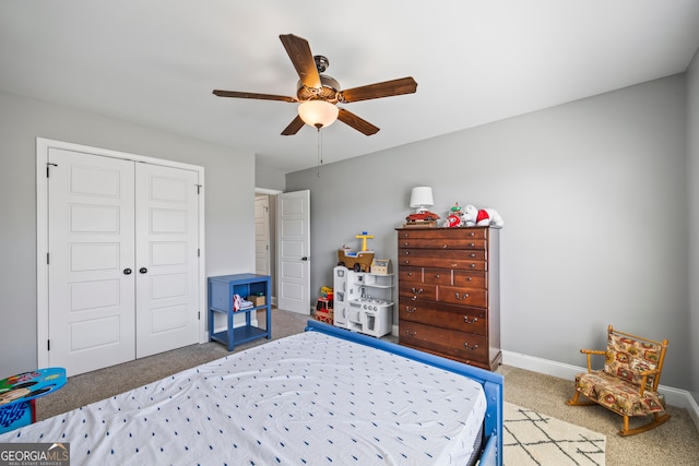 carpeted bedroom with a ceiling fan, a closet, and baseboards