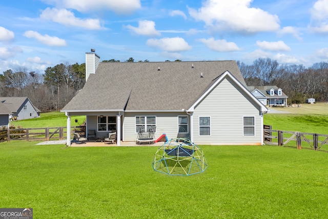 rear view of property with a yard, roof with shingles, a gate, and a patio