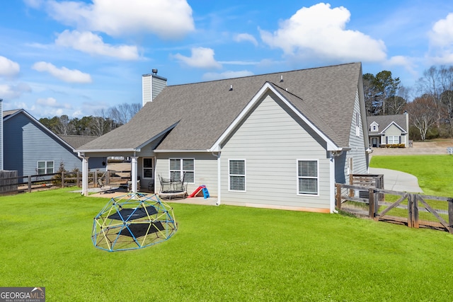 rear view of property with a shingled roof, a lawn, and a gate