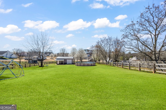 view of yard featuring a fenced backyard, a rural view, a fenced in pool, and an outbuilding