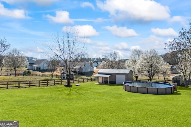 view of yard featuring an outbuilding, fence, a fenced in pool, and a garage