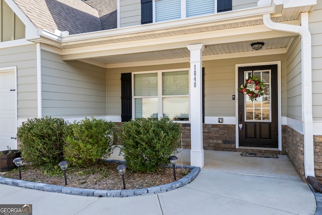 property entrance with a garage, stone siding, and roof with shingles