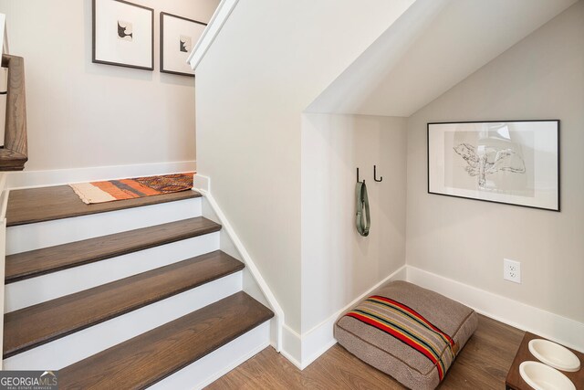 stairway featuring vaulted ceiling, wood finished floors, and baseboards