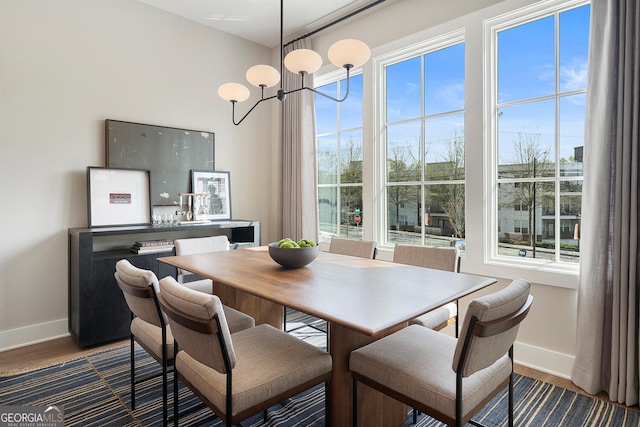 dining room with plenty of natural light, baseboards, dark wood finished floors, and a chandelier