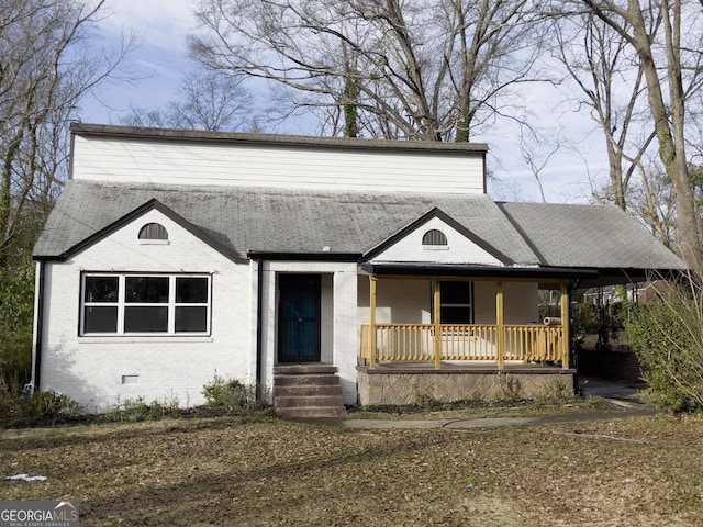 view of front of property with a shingled roof, crawl space, covered porch, and brick siding