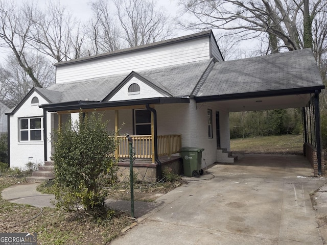 view of front of home with a porch, an attached carport, brick siding, driveway, and roof with shingles