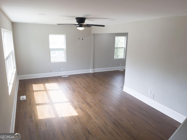 unfurnished room with dark wood-style floors, baseboards, visible vents, and ceiling fan