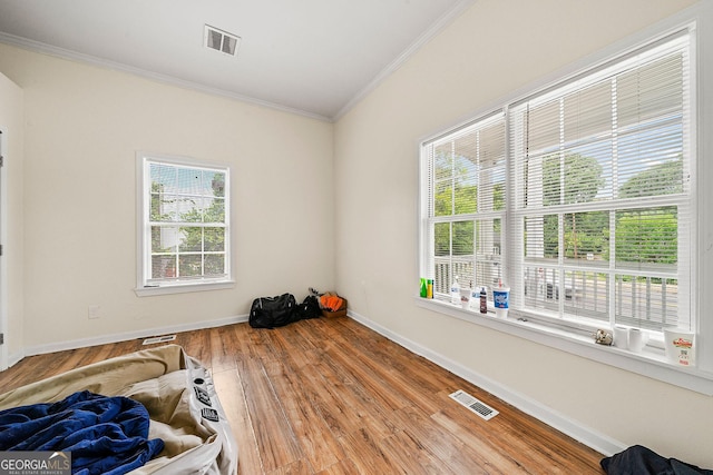 spare room with ornamental molding, visible vents, baseboards, and wood finished floors