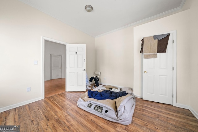 living area with lofted ceiling, baseboards, wood finished floors, and crown molding