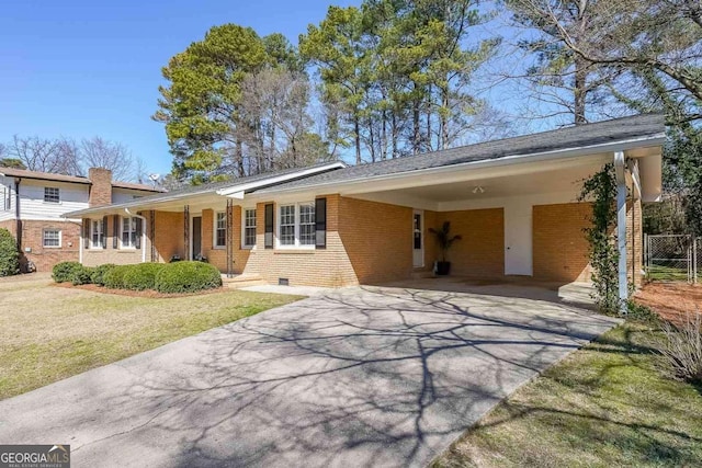 ranch-style house featuring brick siding, fence, driveway, a carport, and a front yard