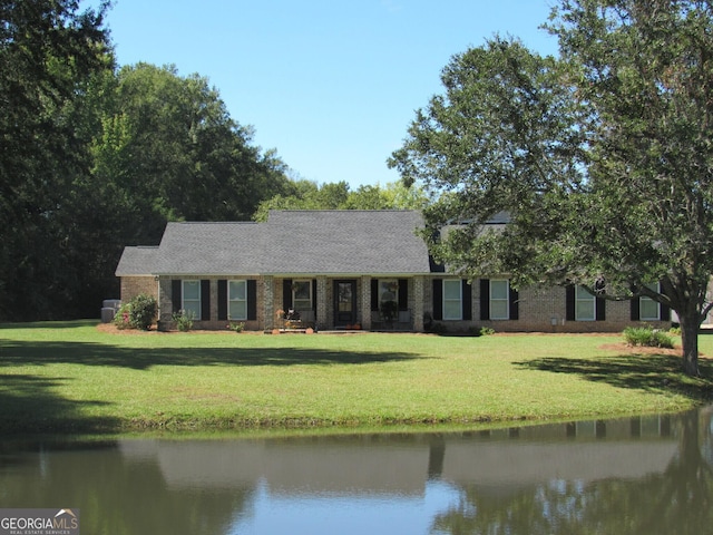 single story home with a front lawn, a water view, and brick siding