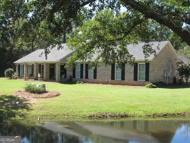 single story home with a shingled roof, a front yard, brick siding, and a water view