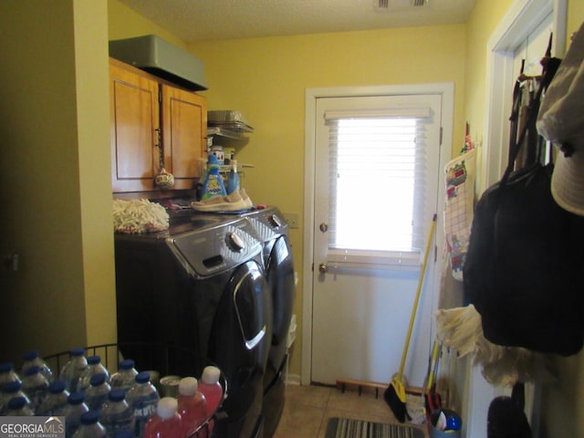 laundry room featuring light tile patterned floors, visible vents, washing machine and clothes dryer, and cabinet space