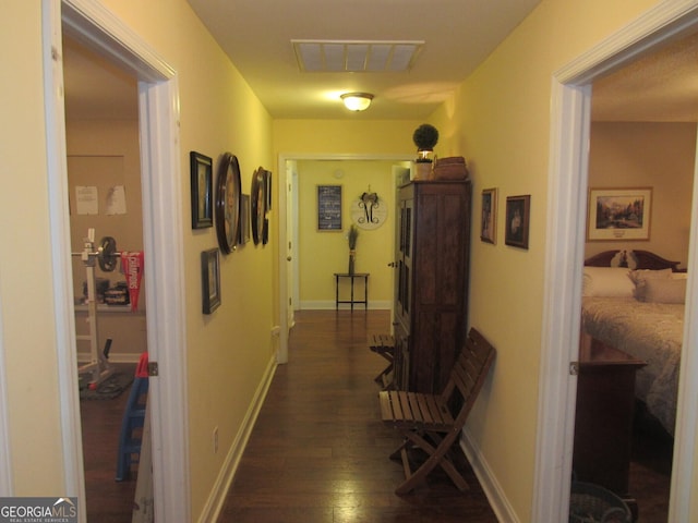 hallway featuring dark wood-type flooring, visible vents, and baseboards