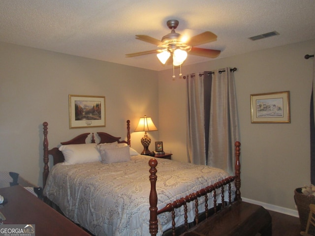 bedroom with baseboards, visible vents, a ceiling fan, wood finished floors, and a textured ceiling