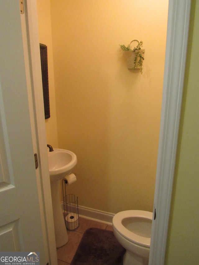 bathroom with tile patterned flooring, toilet, and baseboards