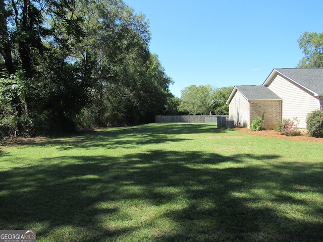 view of yard featuring central AC and fence