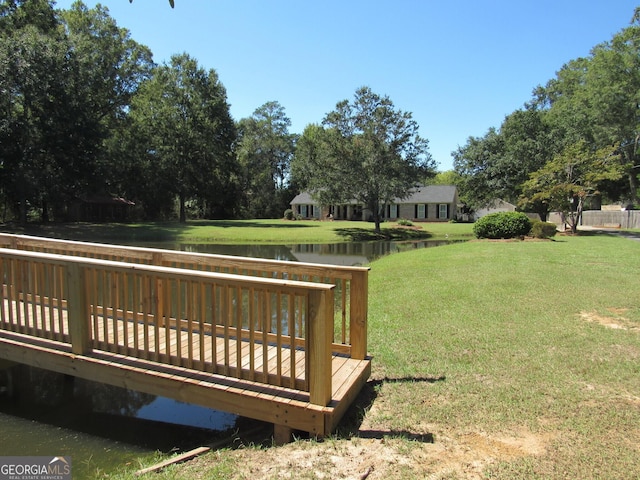 surrounding community featuring a lawn and a deck with water view